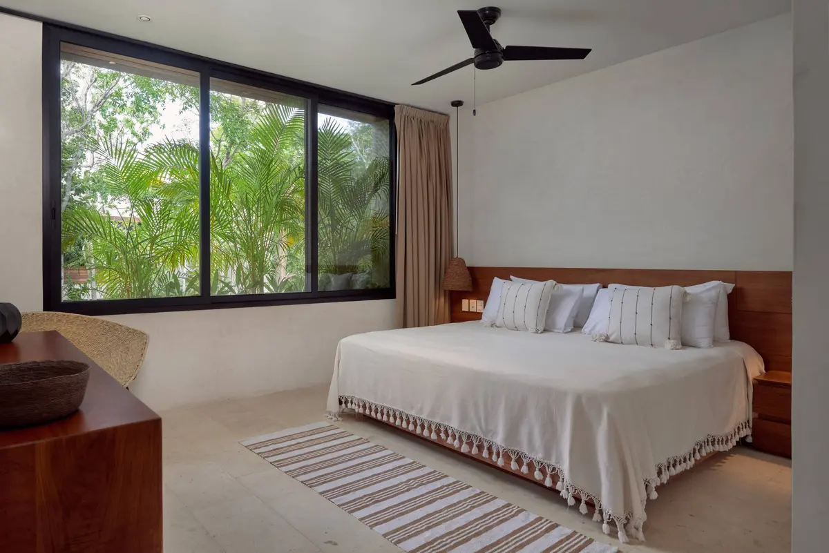 Casa David master bedroom with a king bed under a white tasseled coverlet, a ceiling fan and a wide window onto palms