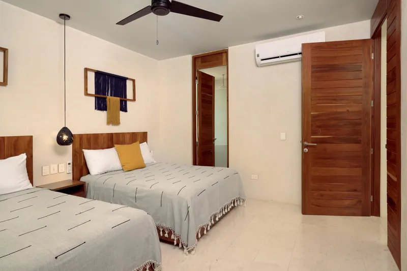 Casa Emilia bedroom with two beds in gray coverlets, a framed wall hanging and wooden doors